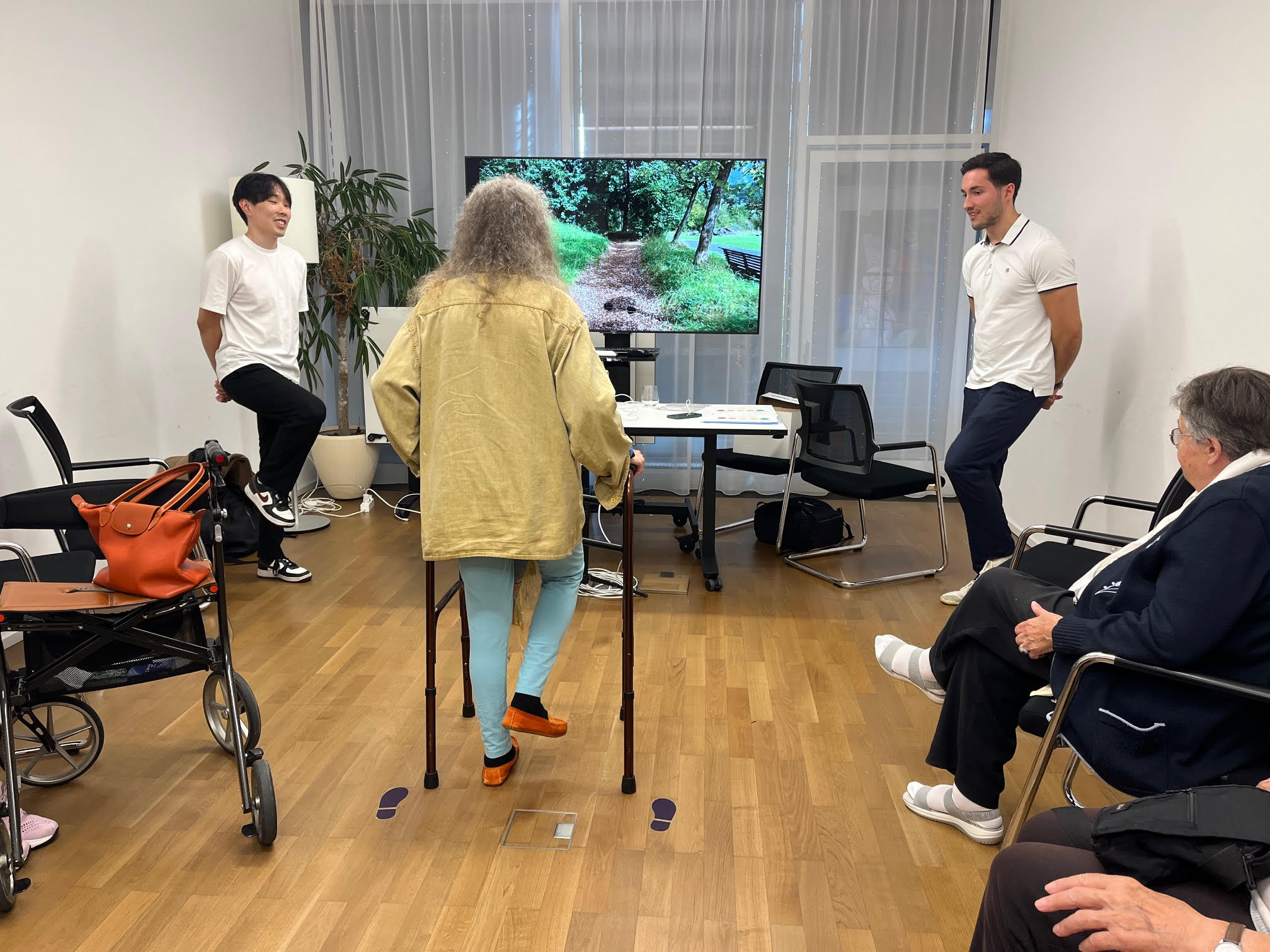 Bewohnerin bewegt sich mit dem Rollator vor der Movoya-Station, begleitet vom Team